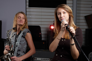 Obraz na płótnie Canvas dwie młode kobiety podpisania piosenki i grać na saksofonie