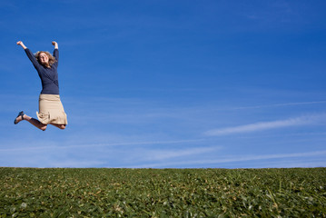 A pretty woman jumps for joy in a field