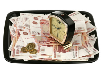 Old alarm clock and new money on a tray