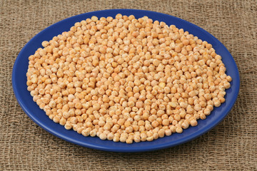 Dry peas in a dark blue plate against a sacking