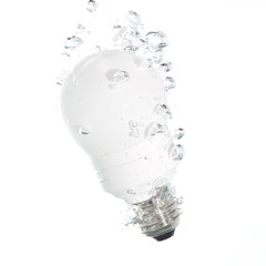 An energy saving light bulb falling into the clear water