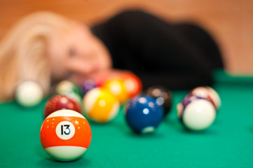 Billiard balls on green table and blond woman
