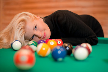 Billiard balls on green table and blond woman