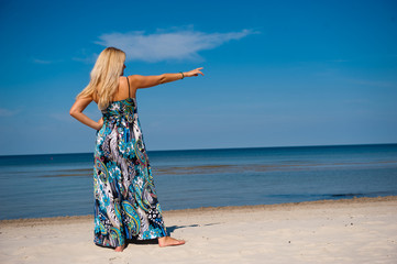 Young beautiful summer girl walking on the beach near sea