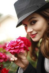 stylish woman wearing a fedora in a rose garden