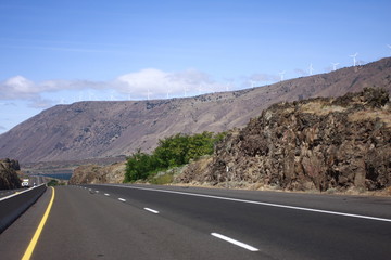 Rural highway with windfarm on top of hill.