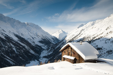 winterscene of alpine valley with snow coverd cabin