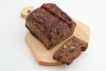 Fototapeta na wymiar Loaf of brown bread and slice on wood board