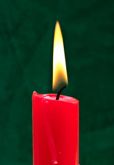 Burning red candle on the green