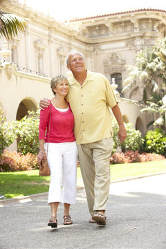 Senior Couple Walking Through City Street