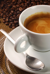 Large esspresso in a white cup surrounded by beans