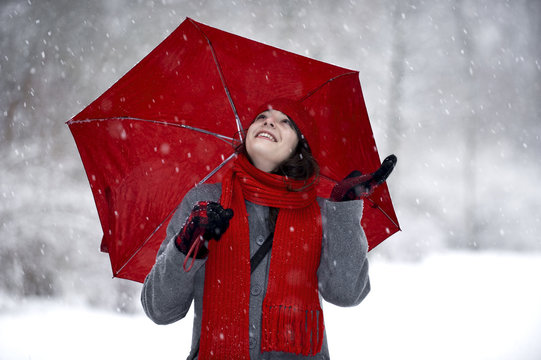Frau im Schnee mit rotem Schirm