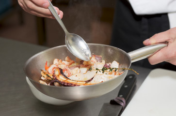 Chef is frying sefood to create delicious dish