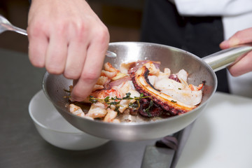 Chef is frying sefood to create delicious dish