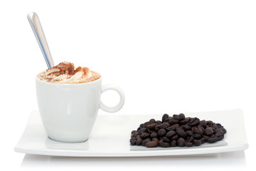 Cappuccino et grains de café disposés sur une soucoupe