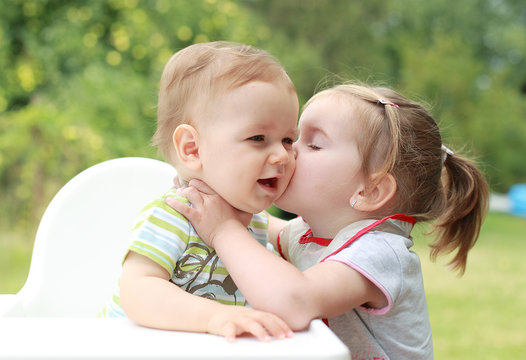Young girl giving kiss for her young brother