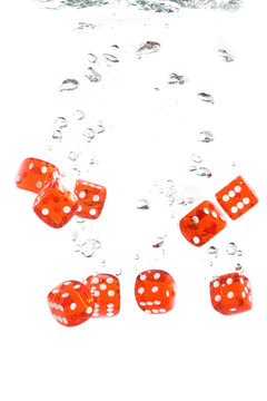 Red transparent dice falling into the clear water