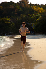 Jugendlicher mit roten Haaren läuft am Strand entland