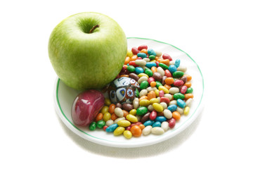 green apple and colorful sweets on the white plate