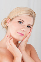 Young woman touching her pure healthy skin applying creme