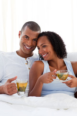 Affectionate couple drinking a cup of tea on their bed