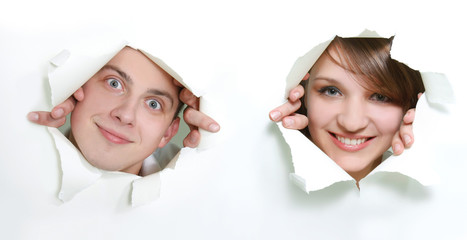 young couple peeping through hole in paper