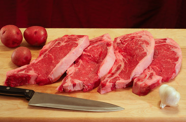 Ingredients for a steak dinner: steaks, potatoes, garlic