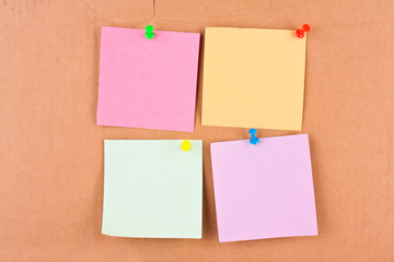 Four blank memo with colourful pins on cardboard