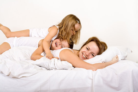 Happy morning - woman and kids on the bed