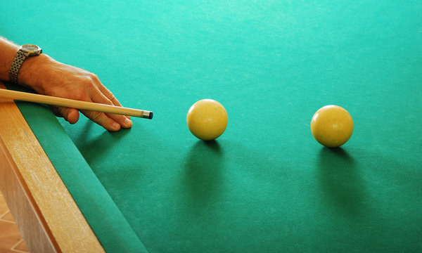 hand with a cue and billiards balls