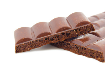 Some slices of black porous chocolate on a white background