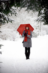 Frau im Schnee mit rotem Schirm
