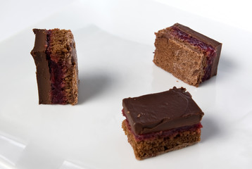 pieces of a dark chocolate cake with sour cherry on a plate in s