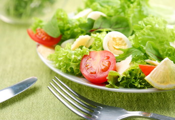 Fresh salad with tomato and quail eggs in a white bowl