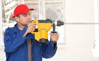 A young handyman holding in his hand a big drill