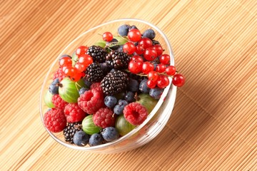 Fruit mix in the glass container, on a table from straw