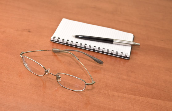 Notepad with eyeglasses and pen
