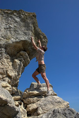 Beautiful young woman climbing on the rock