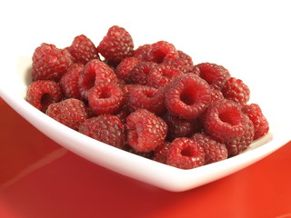 Raspberries on a plate on studio isolated background.