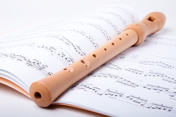 Wooden flute on sheet music. Close up.