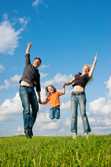 Familie springt auf Wiese im Sommer