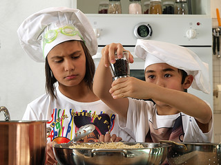 Mädchen und Junge mit Kochmützen kochen