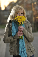 Eine junge blonde Frau hält einen gelben Blumenstrauss