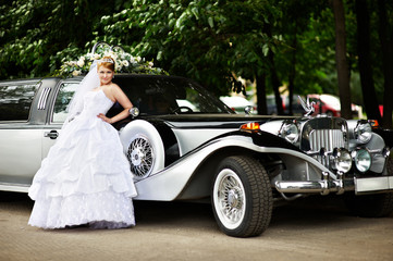 Luxury bride in a wedding dress about retro limousine