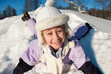 Fototapeta premium Little girl sliding in the snow