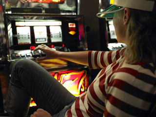 Young Woman Sitting and Playing Slot Machine