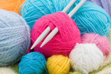 colored wool clews with needles as background