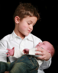 Young boy holds and looks at his new brother