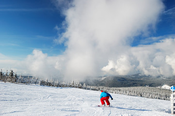 Image of winter day at ski resort with snowboarder at foreground