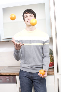 junger mann jongliert mit orangen